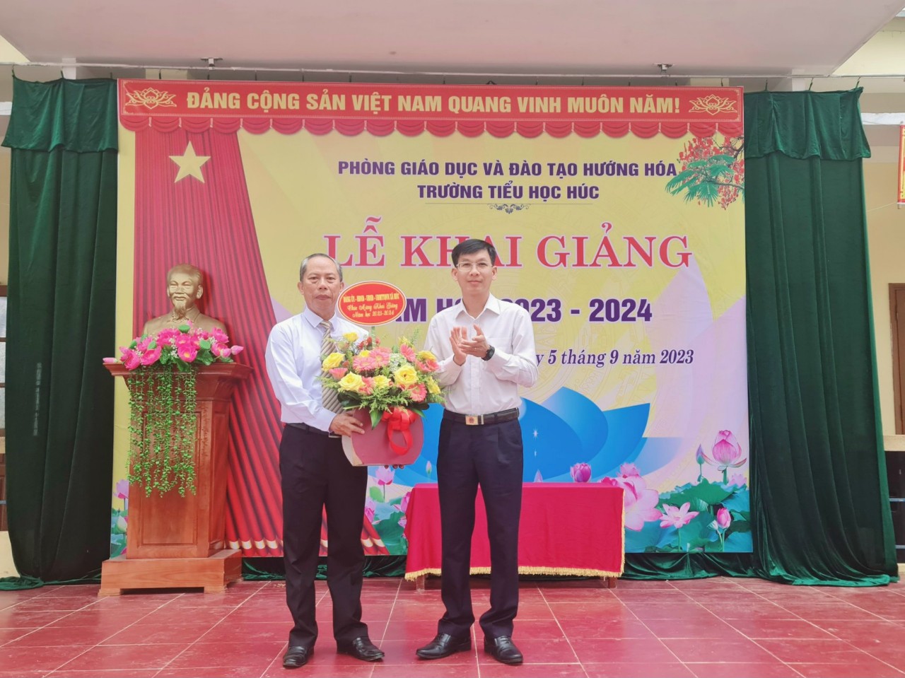 Đồng chí Phạm Huy Văn, Bí thư Đảng ủy xã Húc, huyện Hướng Hóa tặng hoa cho thầy Hiệu trưởng Đoàn Văn Anh.